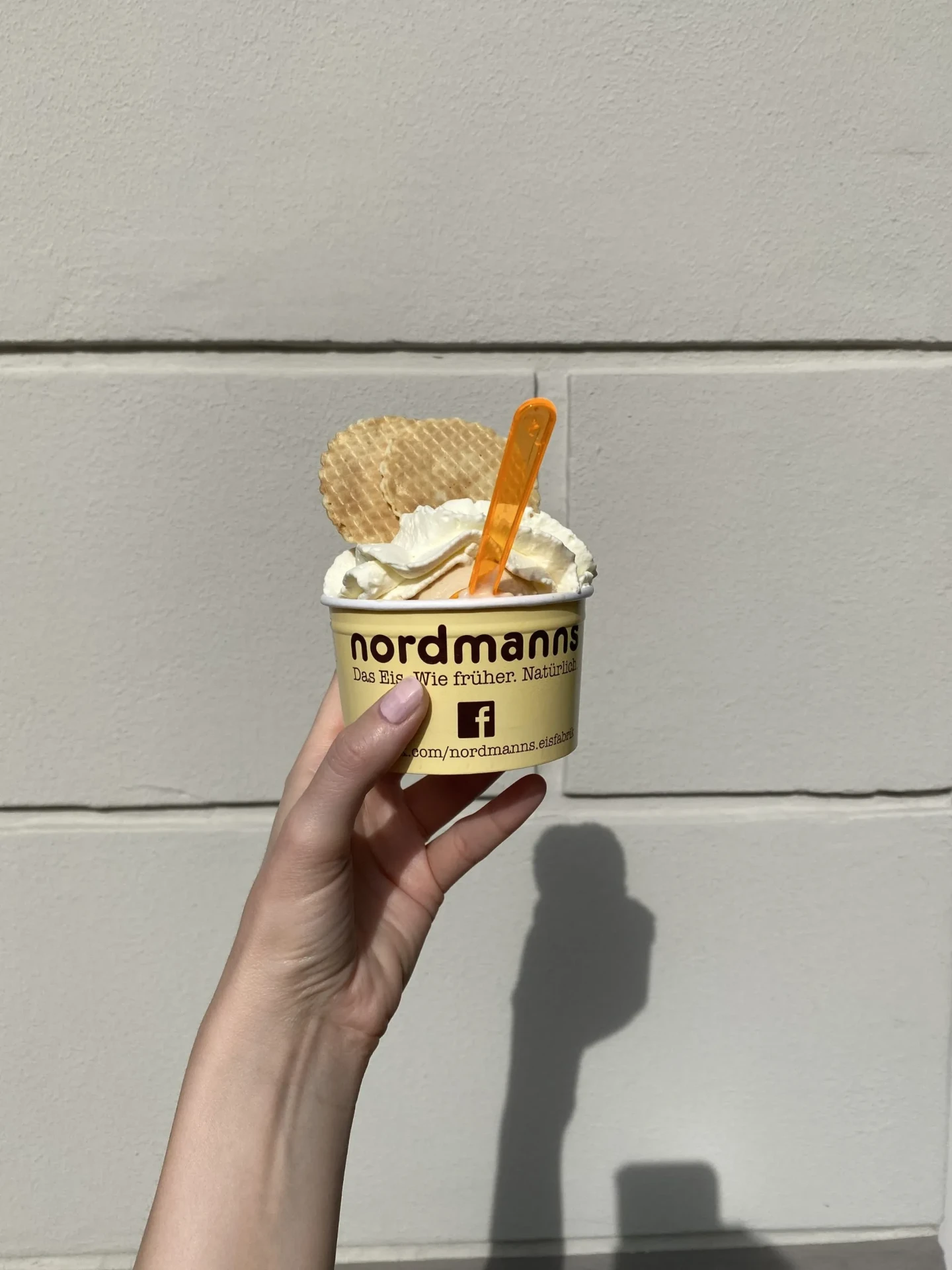 nordmanns Eisbecher mit Sahne und Waffeln in der Hand